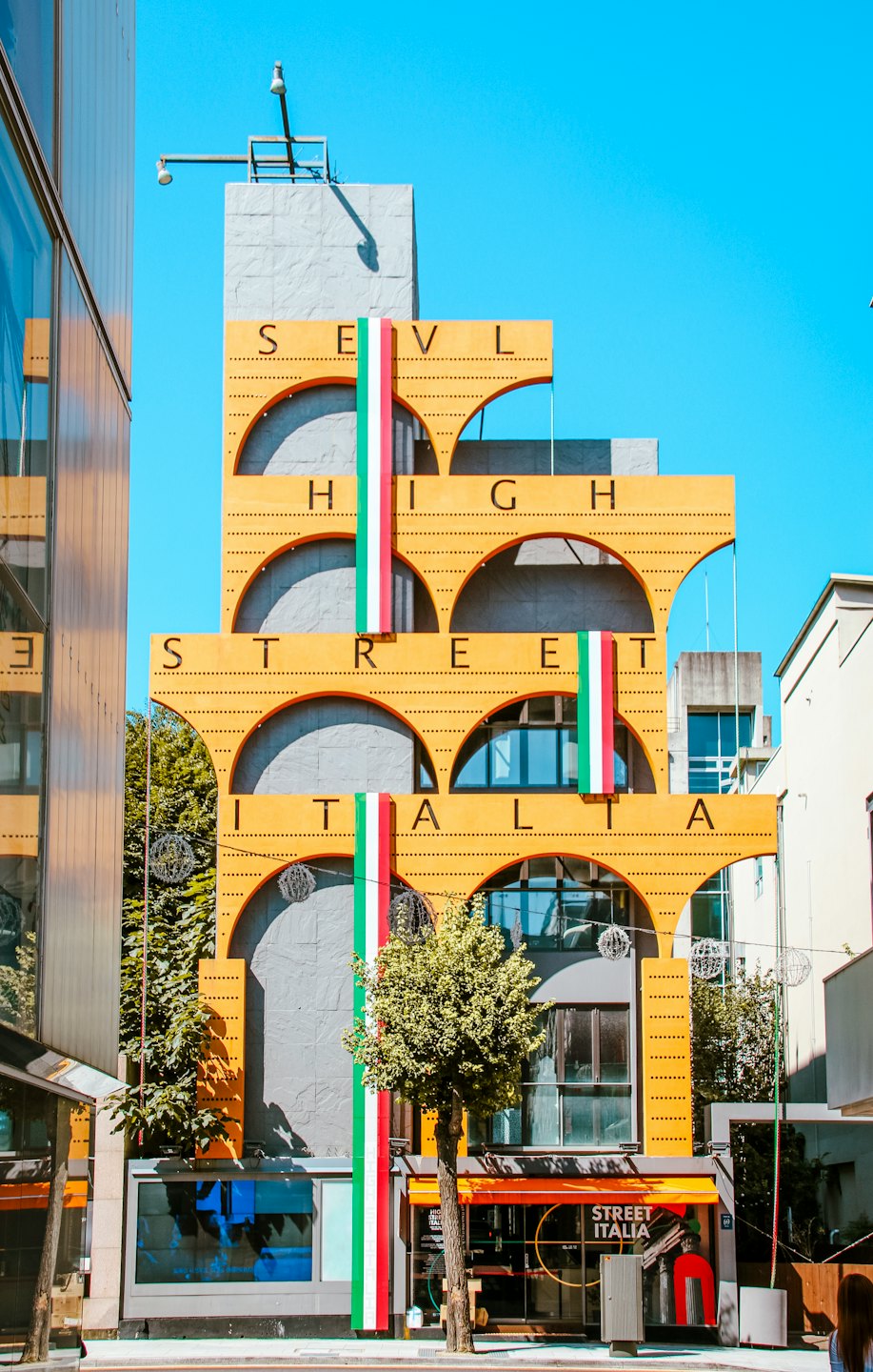 Edificio di High Street Italia con facciata gialla sotto un cielo blu.